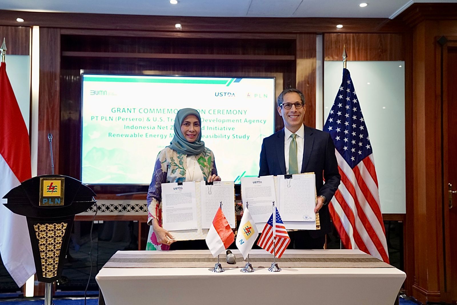 Pertukaran dokumen Grant Agreement “The Indonesia Net Zero World Renewable Energy Mini-Grid” oleh Direktur Keuangan PLN Sinthya Roesly (kiri) dan The Charge d’Affaires ad interim U.S. Embassy Indonesia, Michael F. Kleine (kanan) sebagai simbol komitmen bersama antara PLN dengan USTDA untuk pengembangan EBT di wilayah 3T di Indonesia. ( Foto : Istimewa )